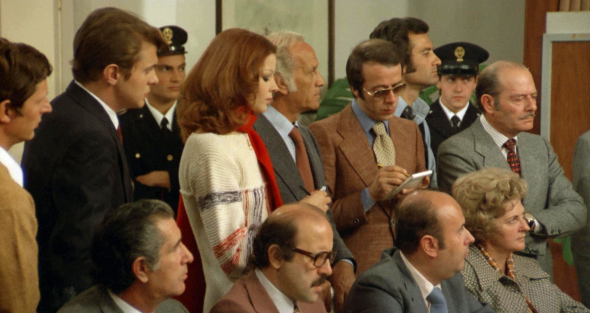 Il poliziotto è marcio (1974) Blonde with pointy chin at press conference.jpg